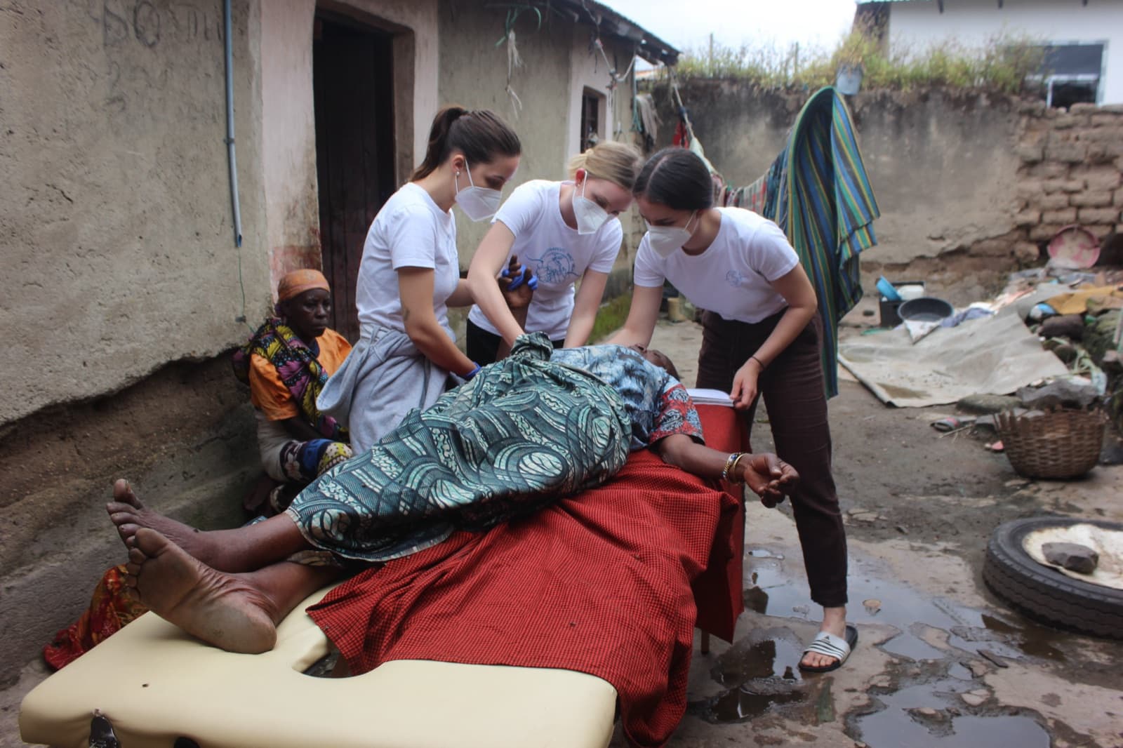 Three physiotherapists treating a woman in the field in Mbeya, Tanzania.